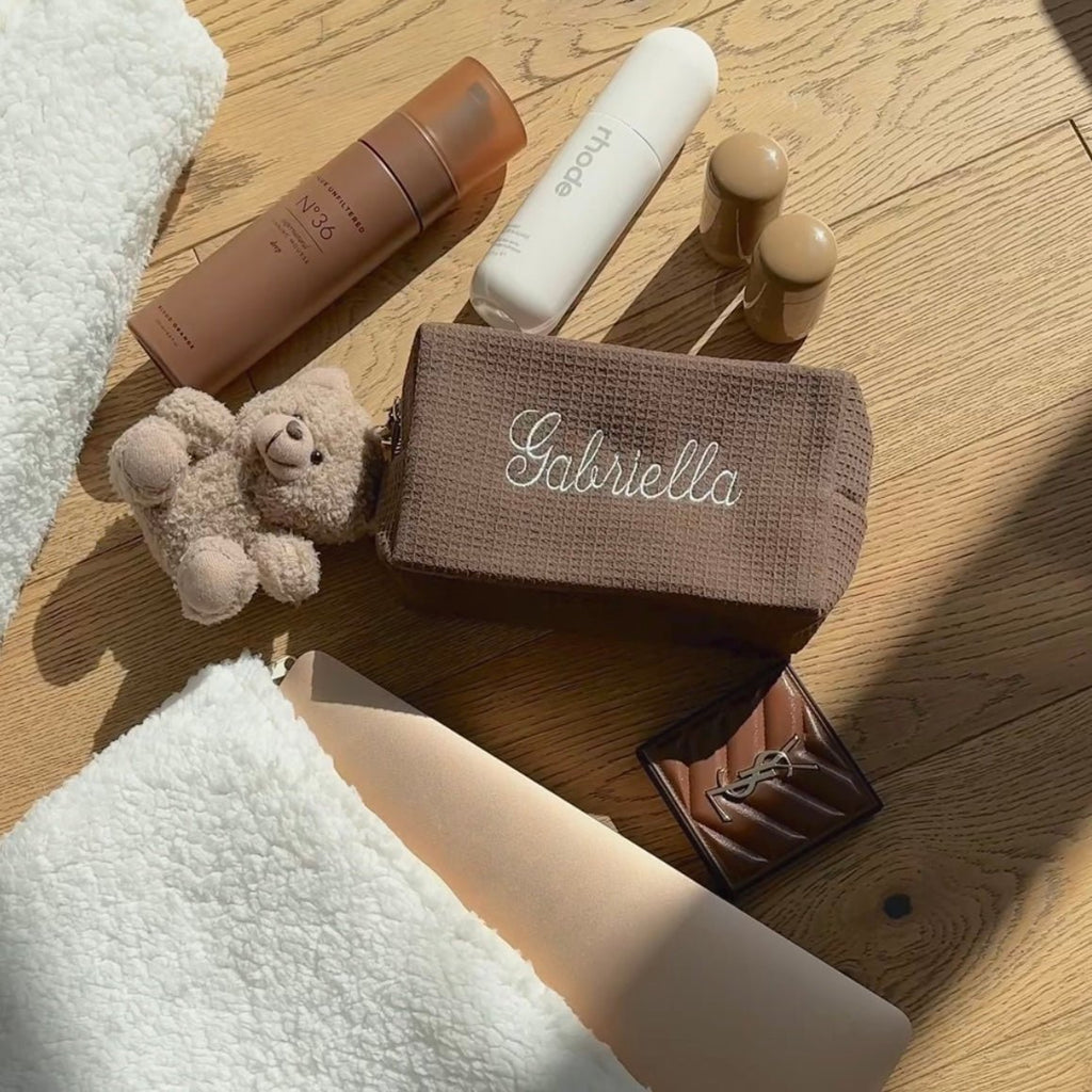 Brown waffle-knit pouch with white cursive embroidery, rectangular shape