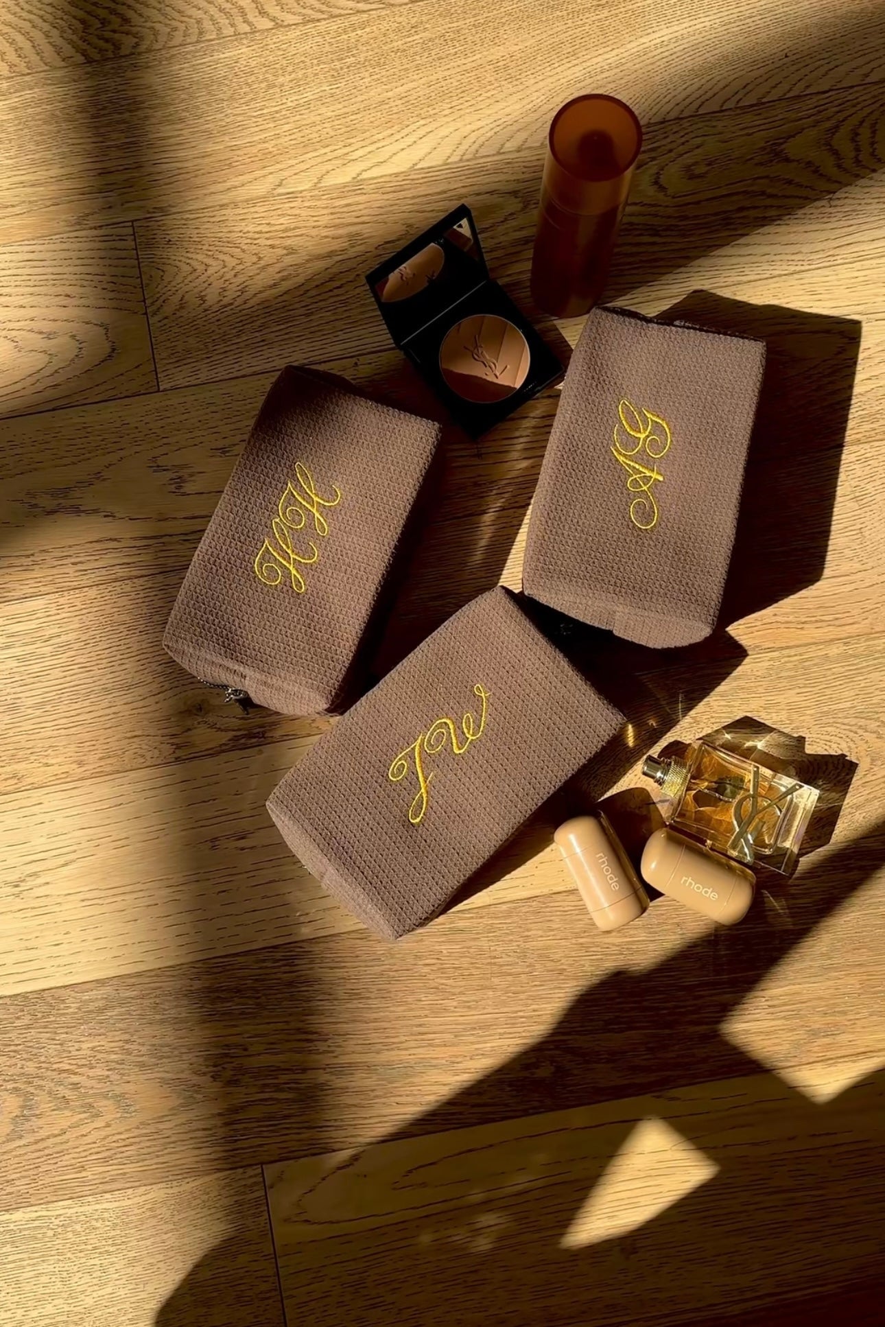 Brown waffle-knit pouches with yellow cursive embroidery, slim rectangular design