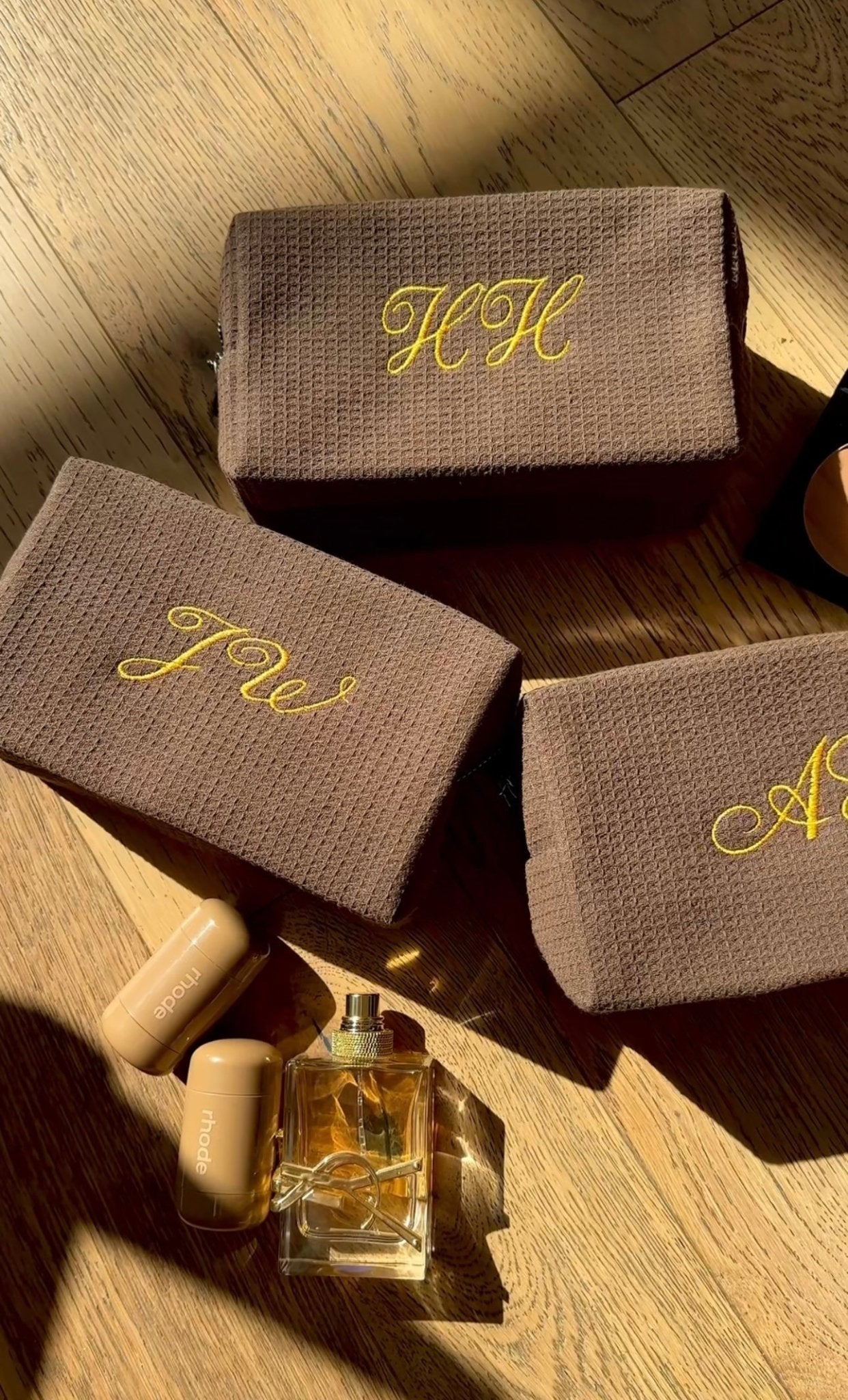 Brown waffle-knit pouch with yellow cursive embroidery on the front