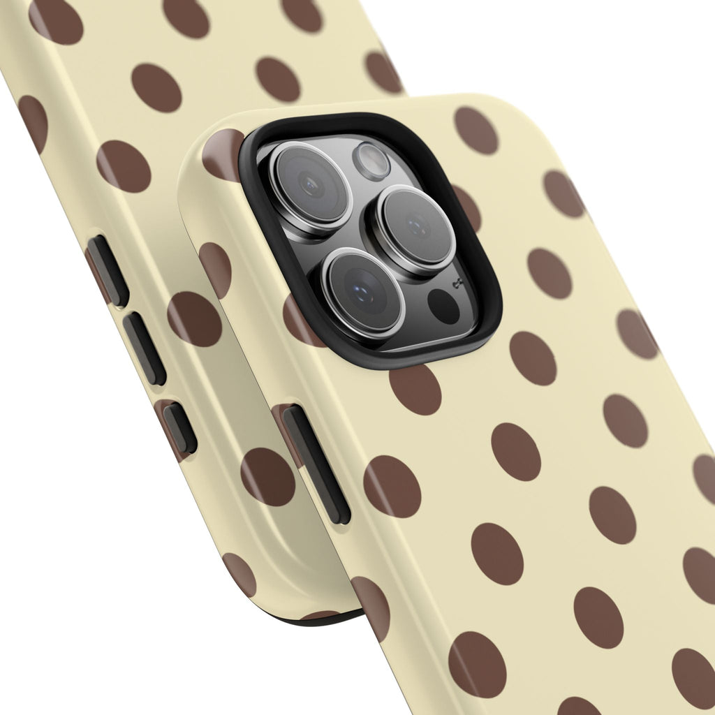 Close-up corner of butter yellow phone case with brown polka dots and camera lens cover