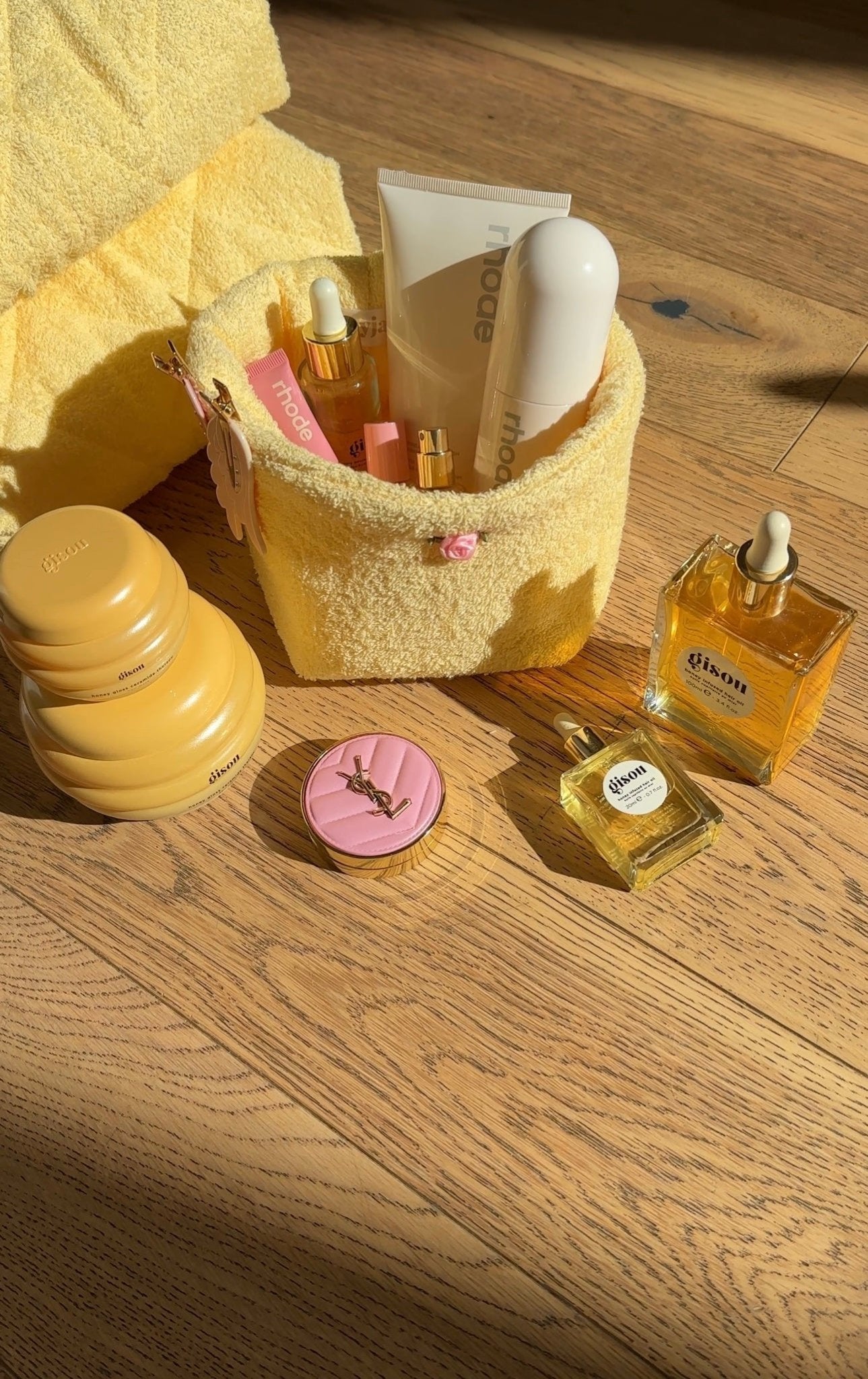 Butter yellow terrycloth organizer holding bottles, cream jar, and pink cap
