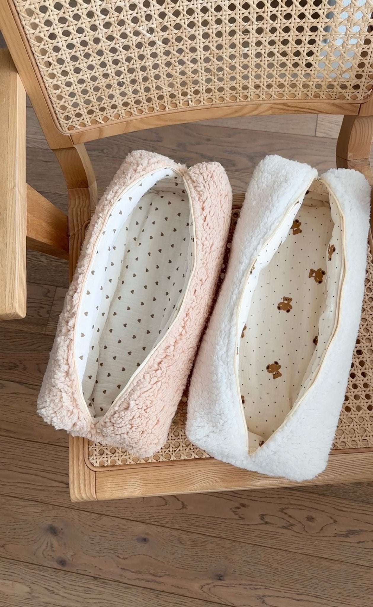 Two plush teddy pouches with zip openings, cream and blush exteriors, open compartments