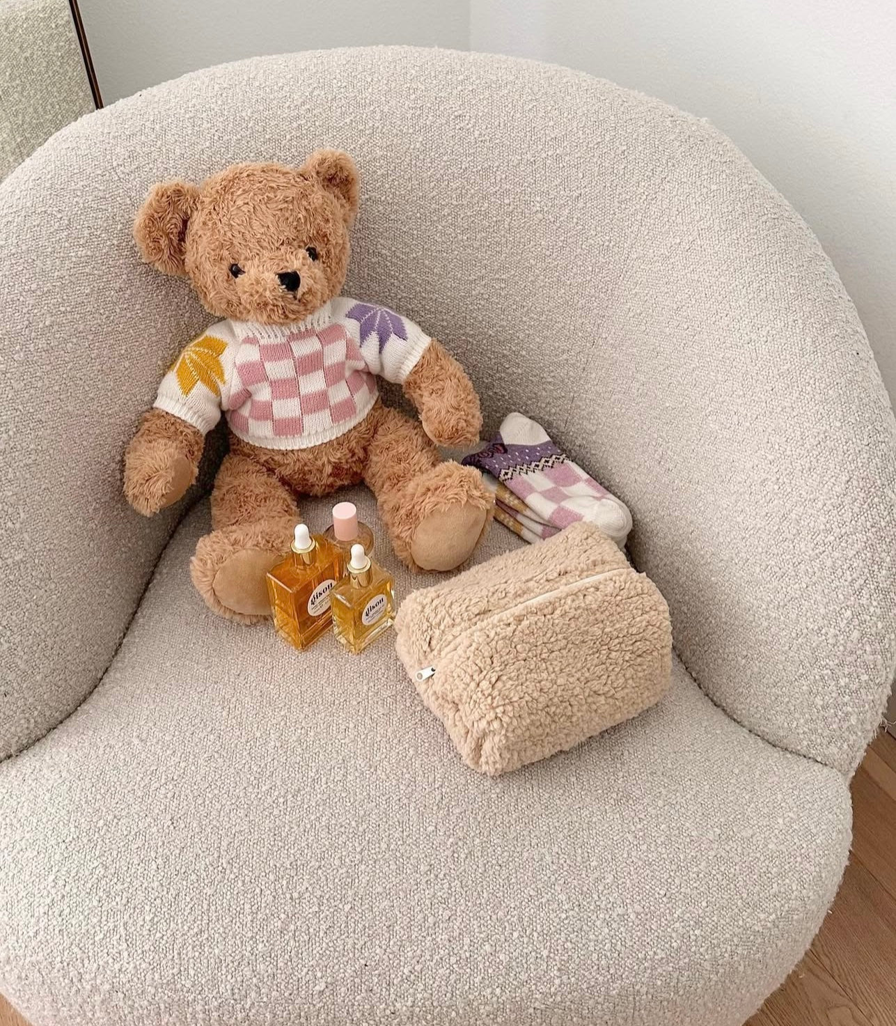 Camel teddy pouch on couch with small teddy bear and patterned knit pouch inside.