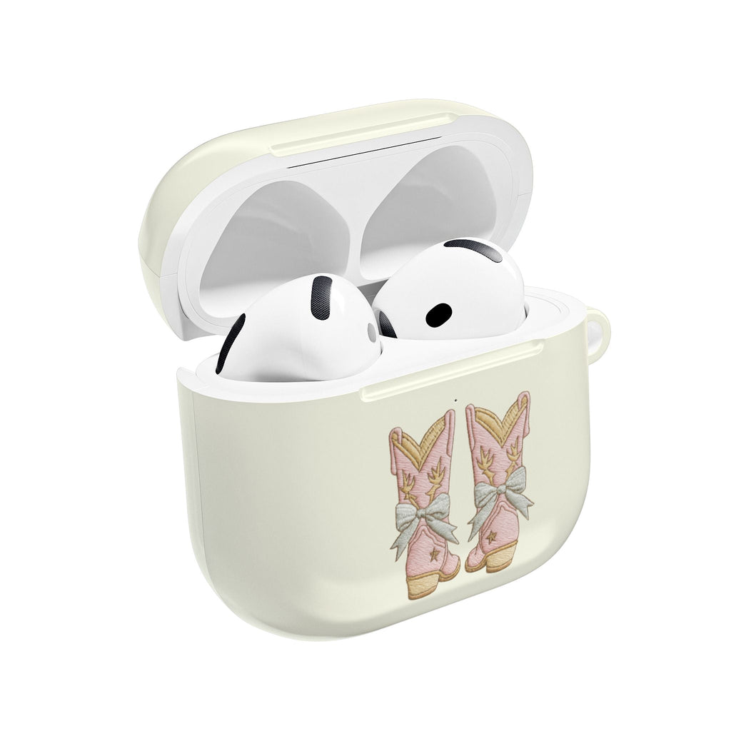 Light cream AirPod case, open lid, cowboy boot bow graphic with white earbuds