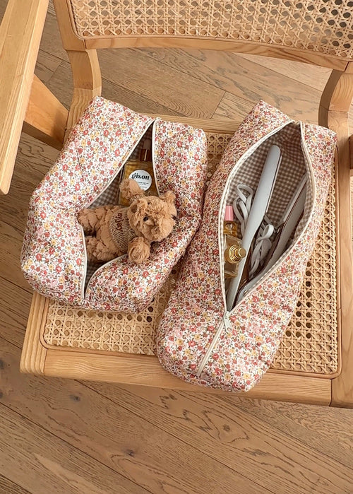 Two white floral zip pouches, one open with toiletries; lined interior visible