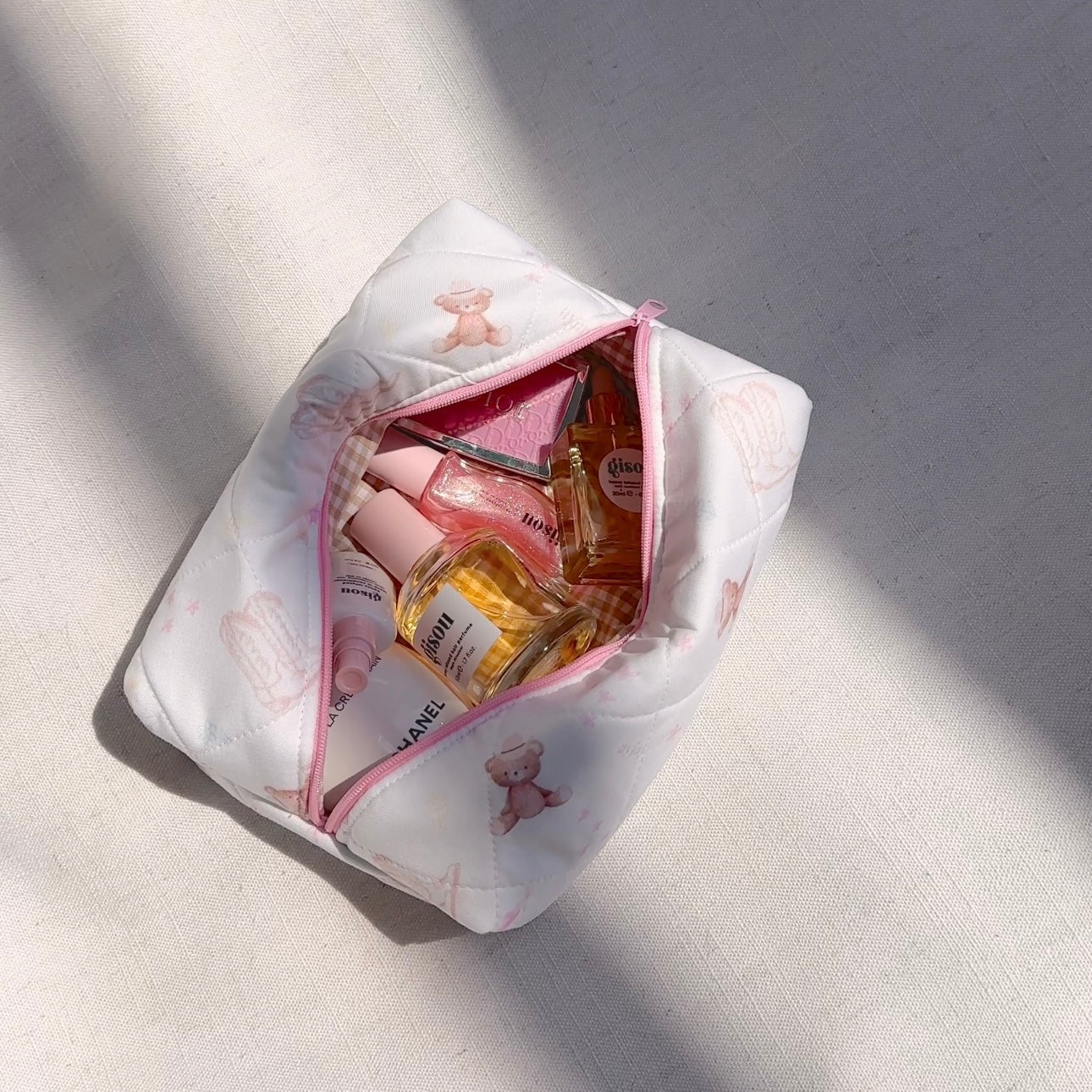 White quilted pouch open with pink zipper and teddy bear print