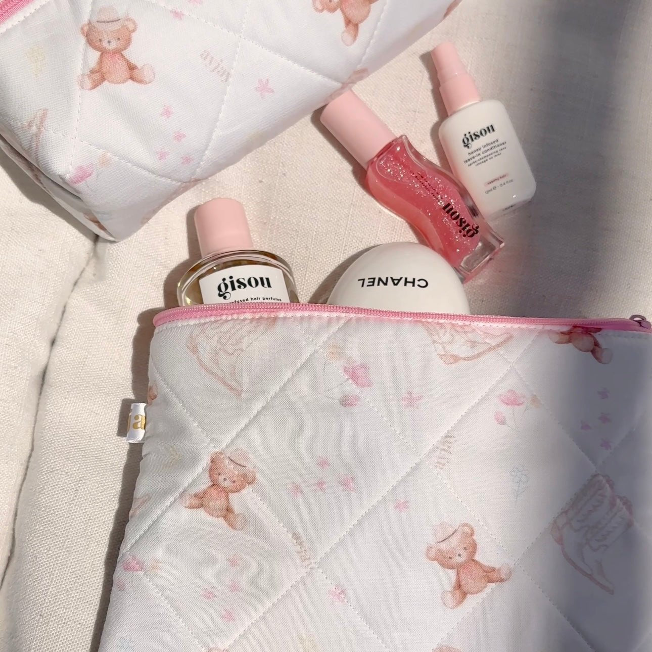 Close-up quilted white pouch with teddy bear print and pink zip