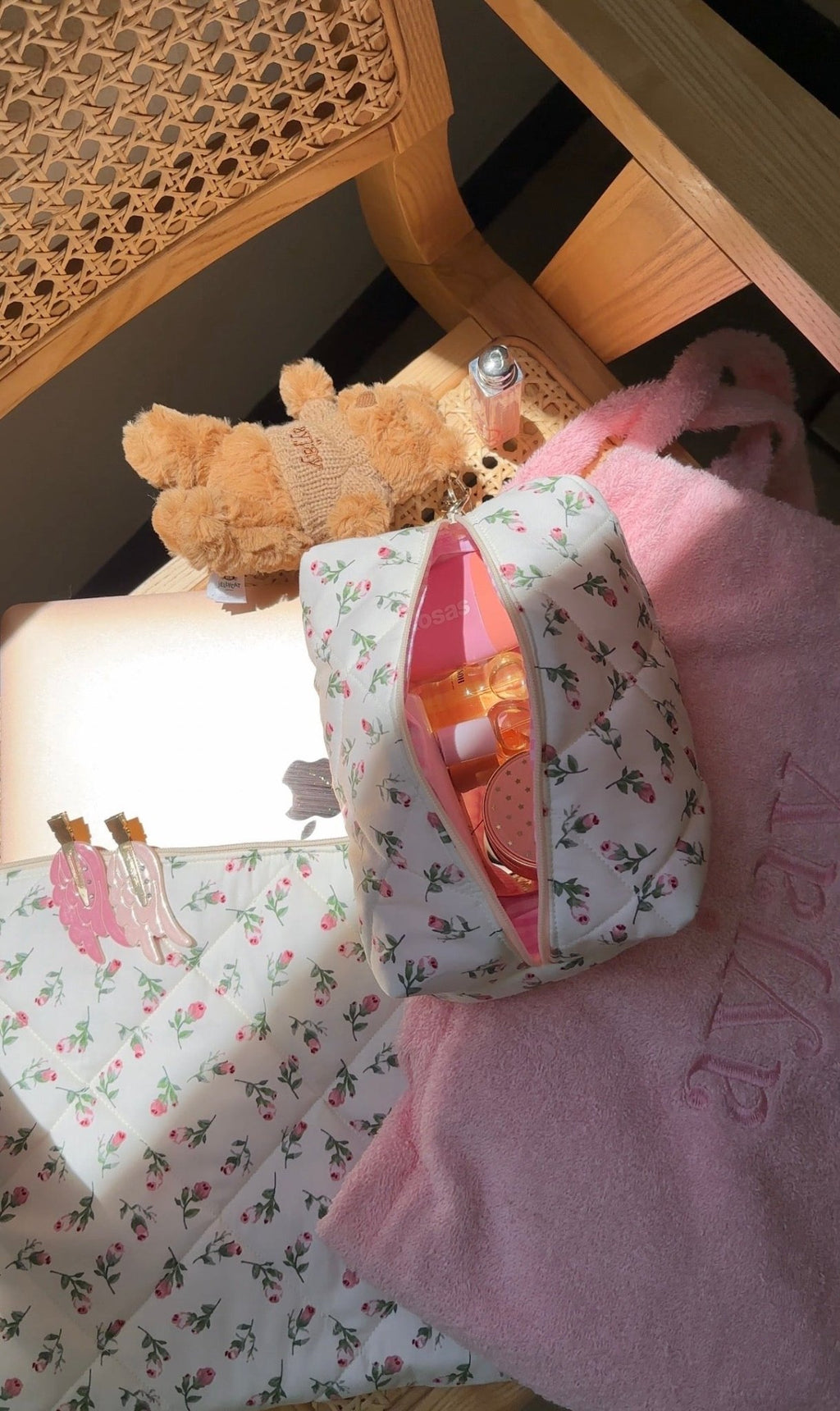 Cream floral toiletry pouch with pink trim, held open with toiletries visible