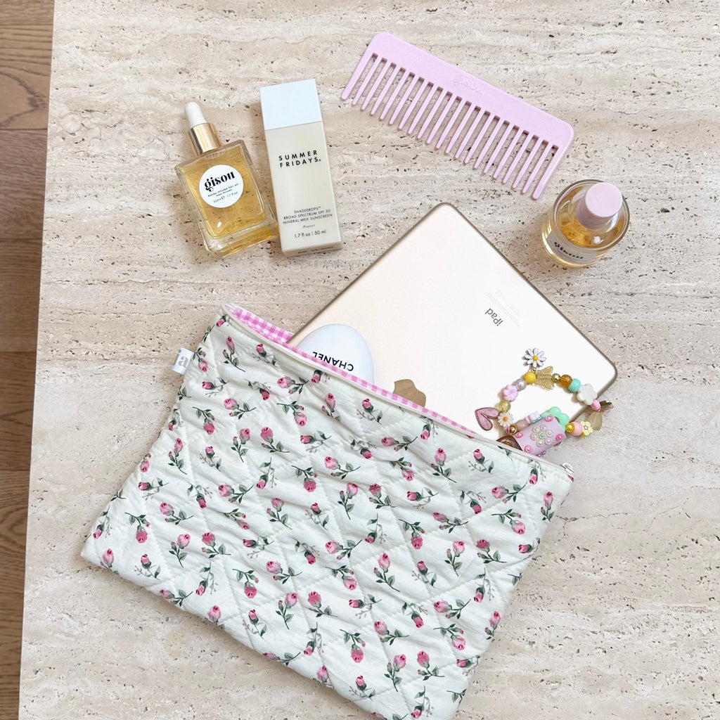 Cream floral quilted zip pouch with pink trim, laid on surface