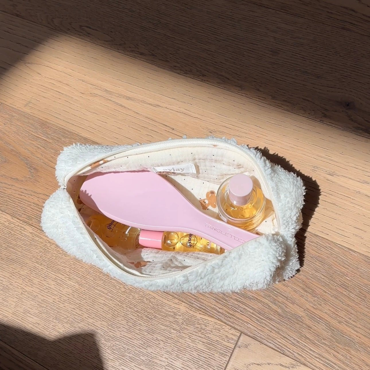 Cream teddy pouch open with inner lining and zip closure, plush outer texture