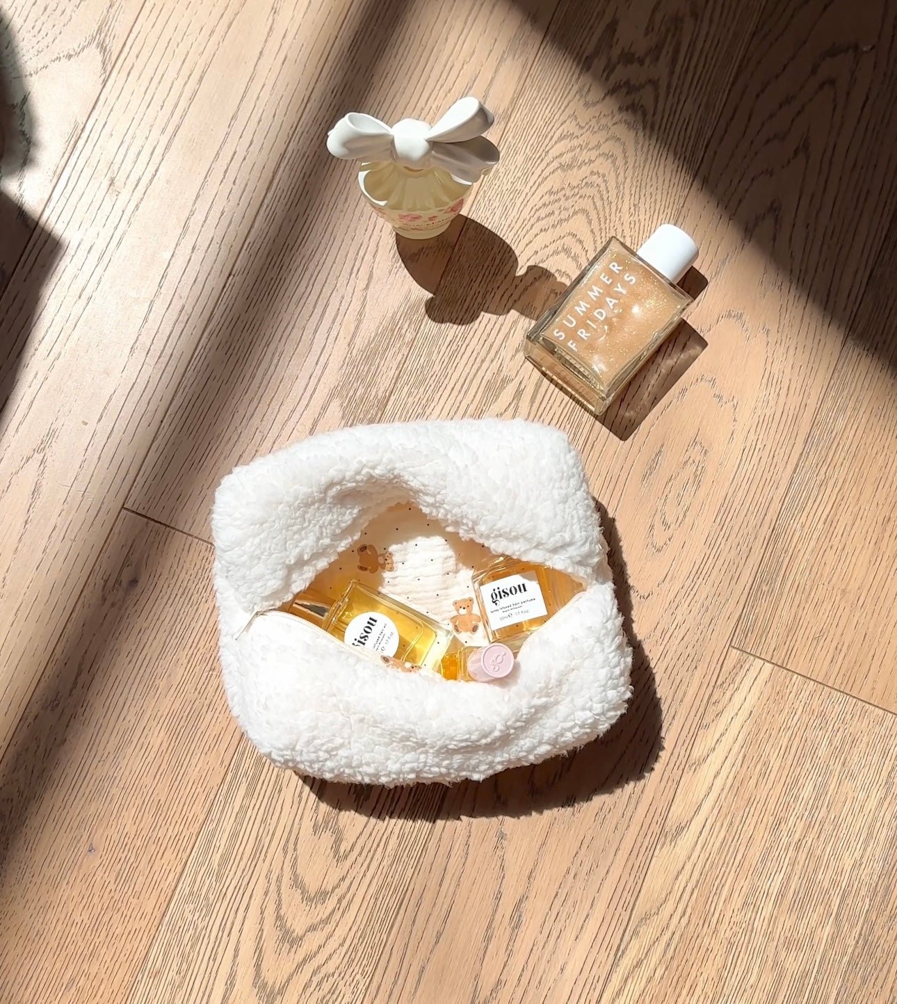 Cream plush teddy-style pouch with zip top, front bow detail, soft textured exterior