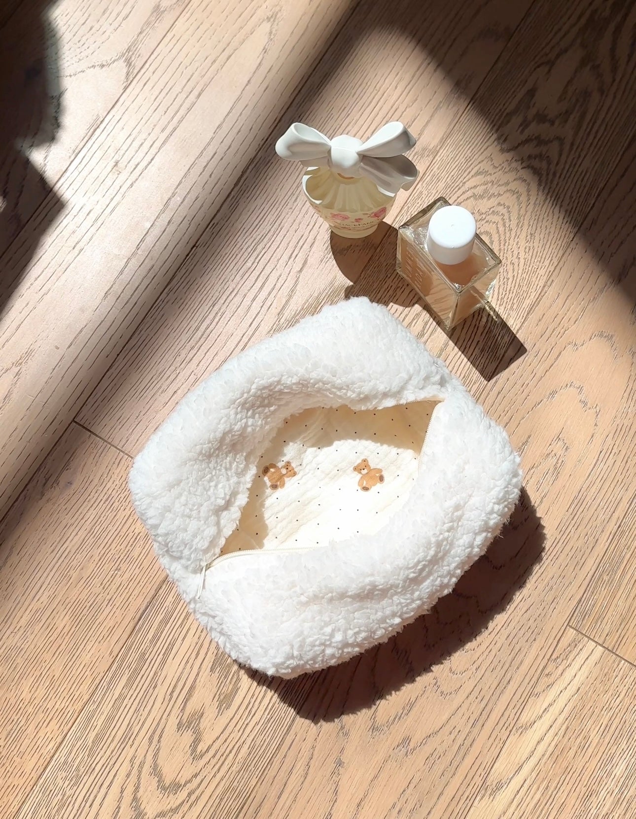 Cream plush teddy-style pouch with bow handle, zip top, soft textured fabric