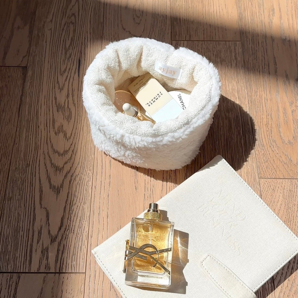 Cream soft teddy round organizer with inner pocket, styled with perfume bottle and white card