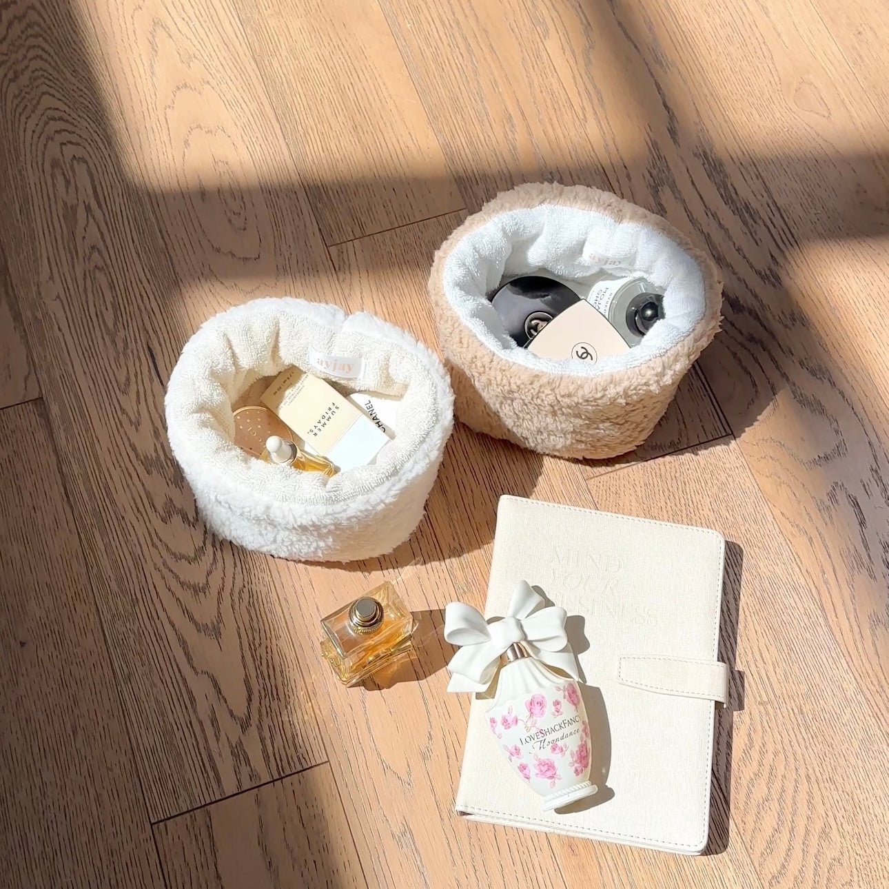 Cream teddy round organizers (set of two) on wood with mini perfume bottles and notebook