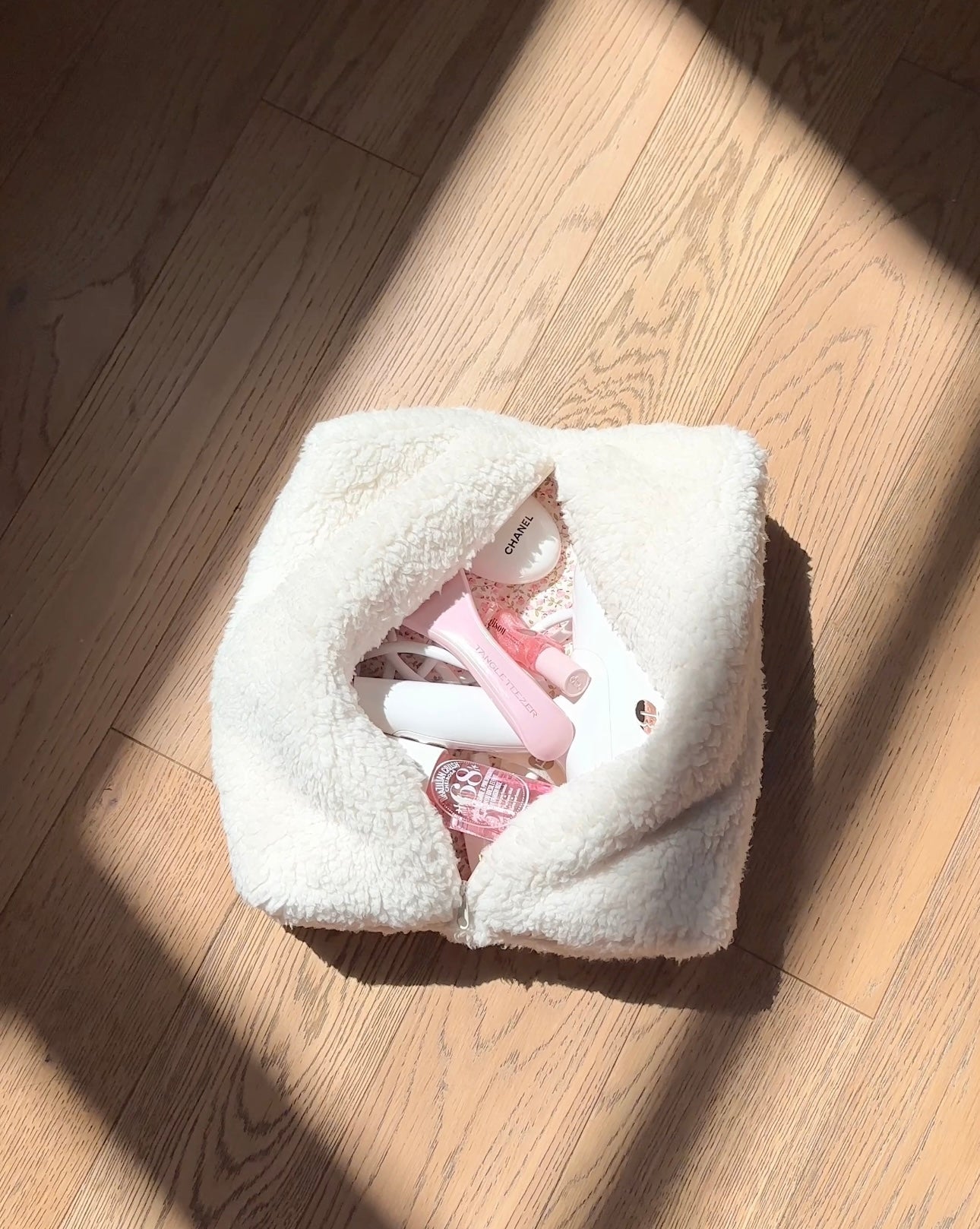 Cream teddy pouch with zip closure, viewed from above on light wood flooring