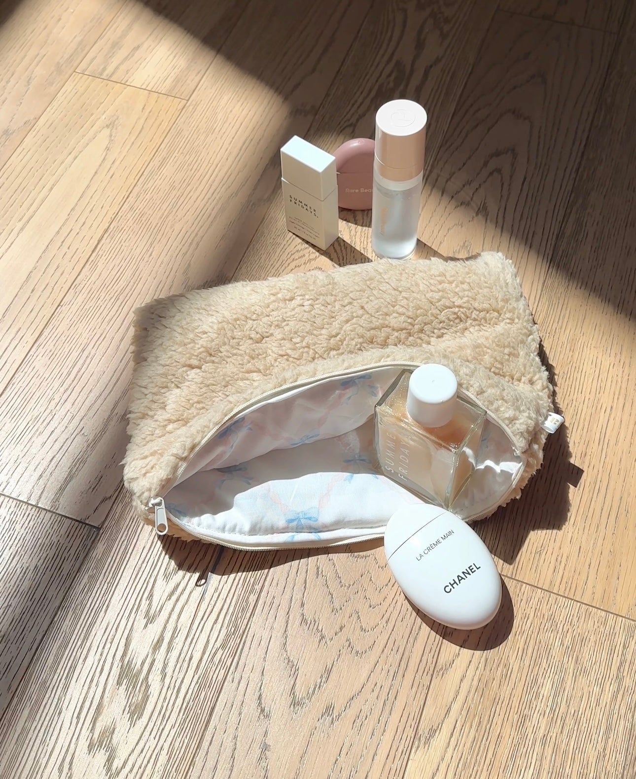 Cream sherpa makeup pouch, open with bottles and a compact inside