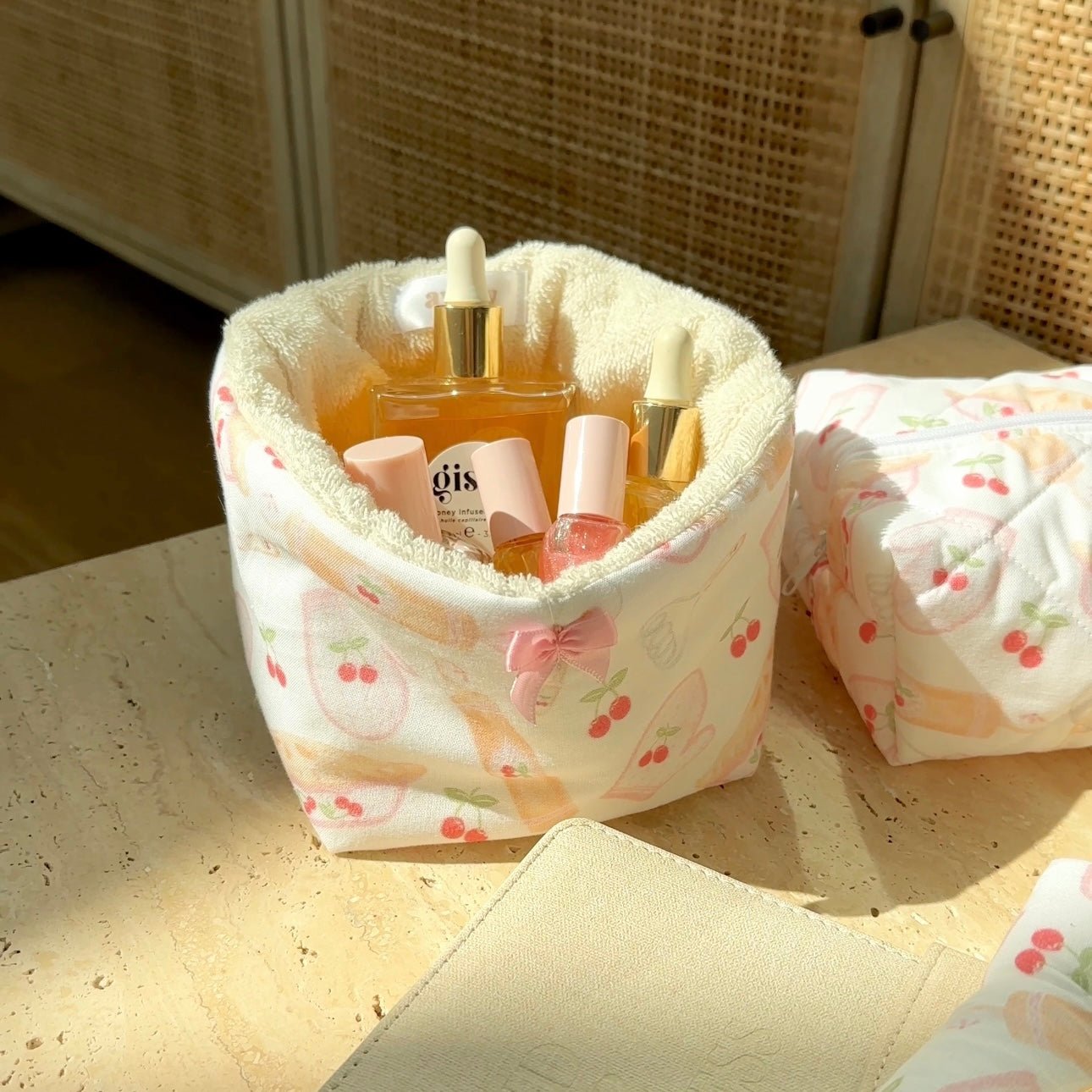 Cherry-pattern teddy makeup organizer with plush rim and pink bow, holding bottles