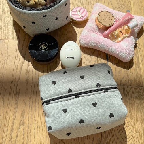 Light gray heart-print zip pouch with black hearts, flat fold and zipper