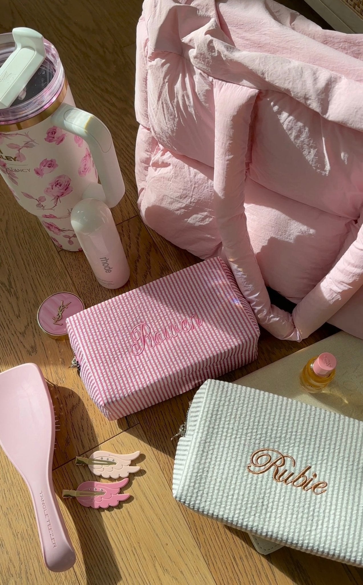 Light pink striped embroidered bag with bow handles, plus mint “Rubie” pouch on floor