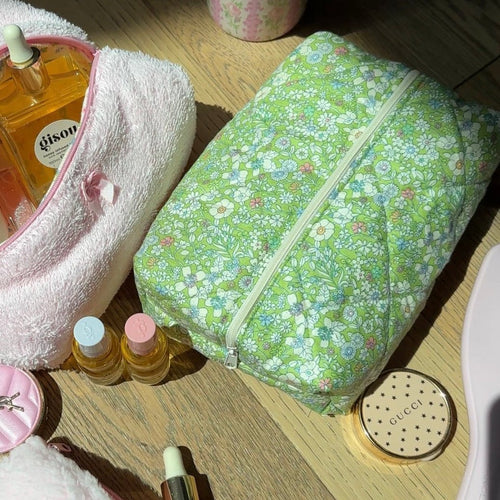 Green floral toiletry pouch with pale zipper, angled view