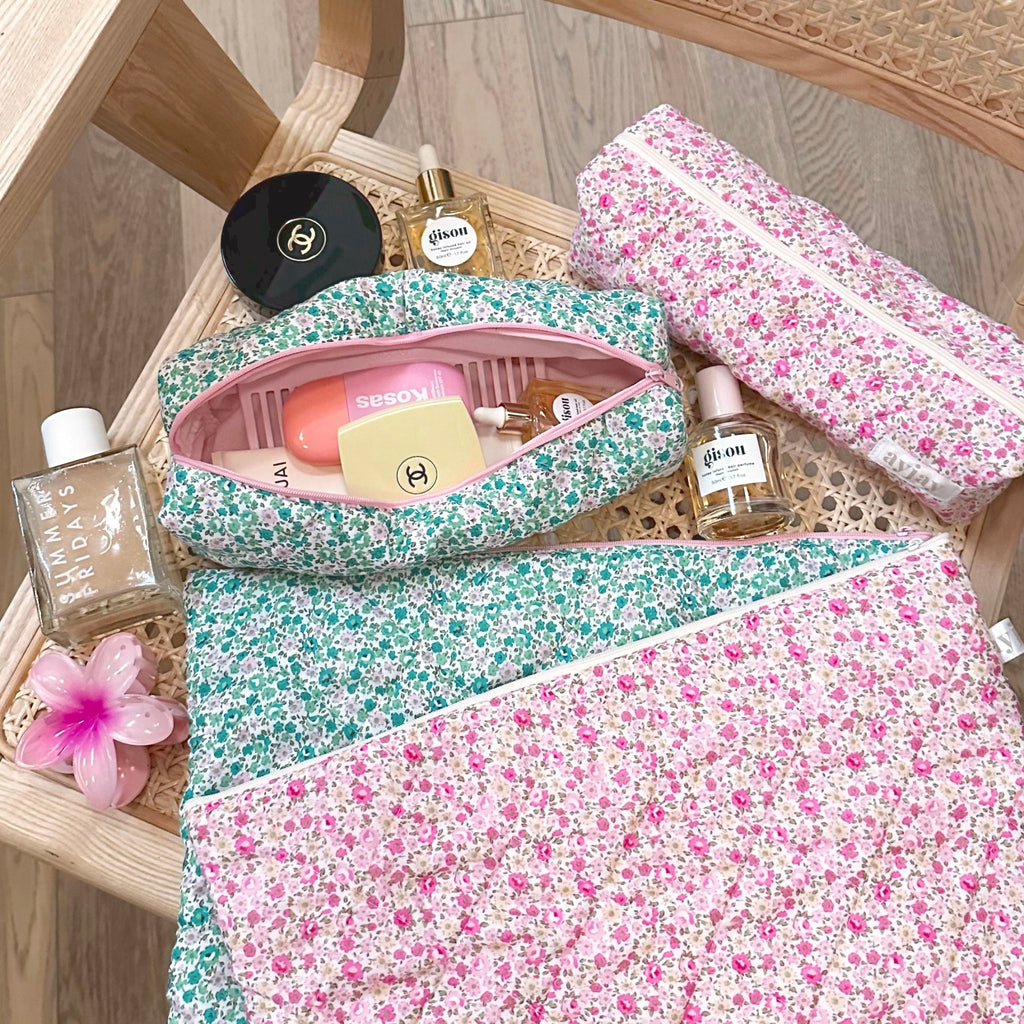 Set of green floral and pink floral pouches with pink zippers, filled with beauty items