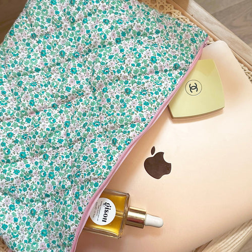 Green and pink floral zip pouch with pink zipper trim, partially filled with bottles