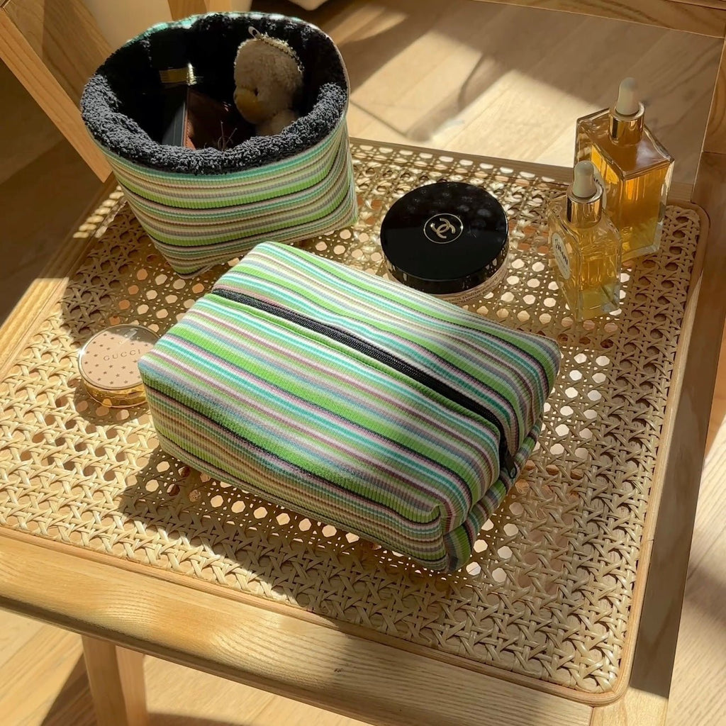 Green striped zip pouch with black trim and folded front, standing upright