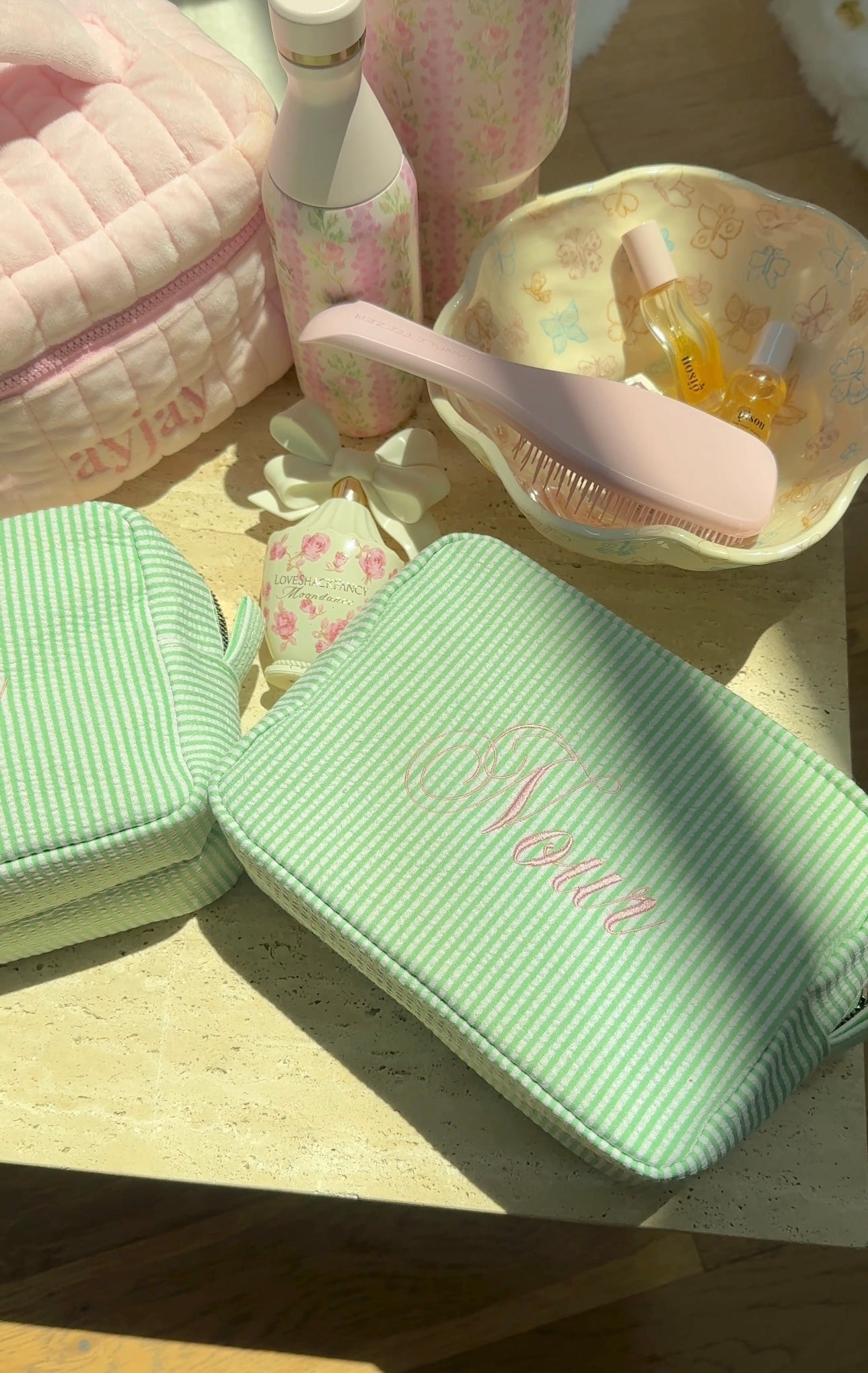 Green striped zipped pouch bag with embroidered name on front panel; quilted texture.