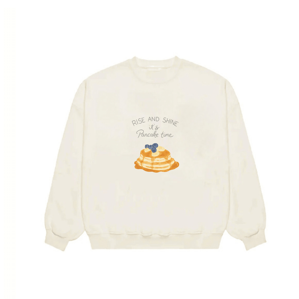Ivory crewneck sweatshirt front view with 'Rise and Shine' pancake graphic