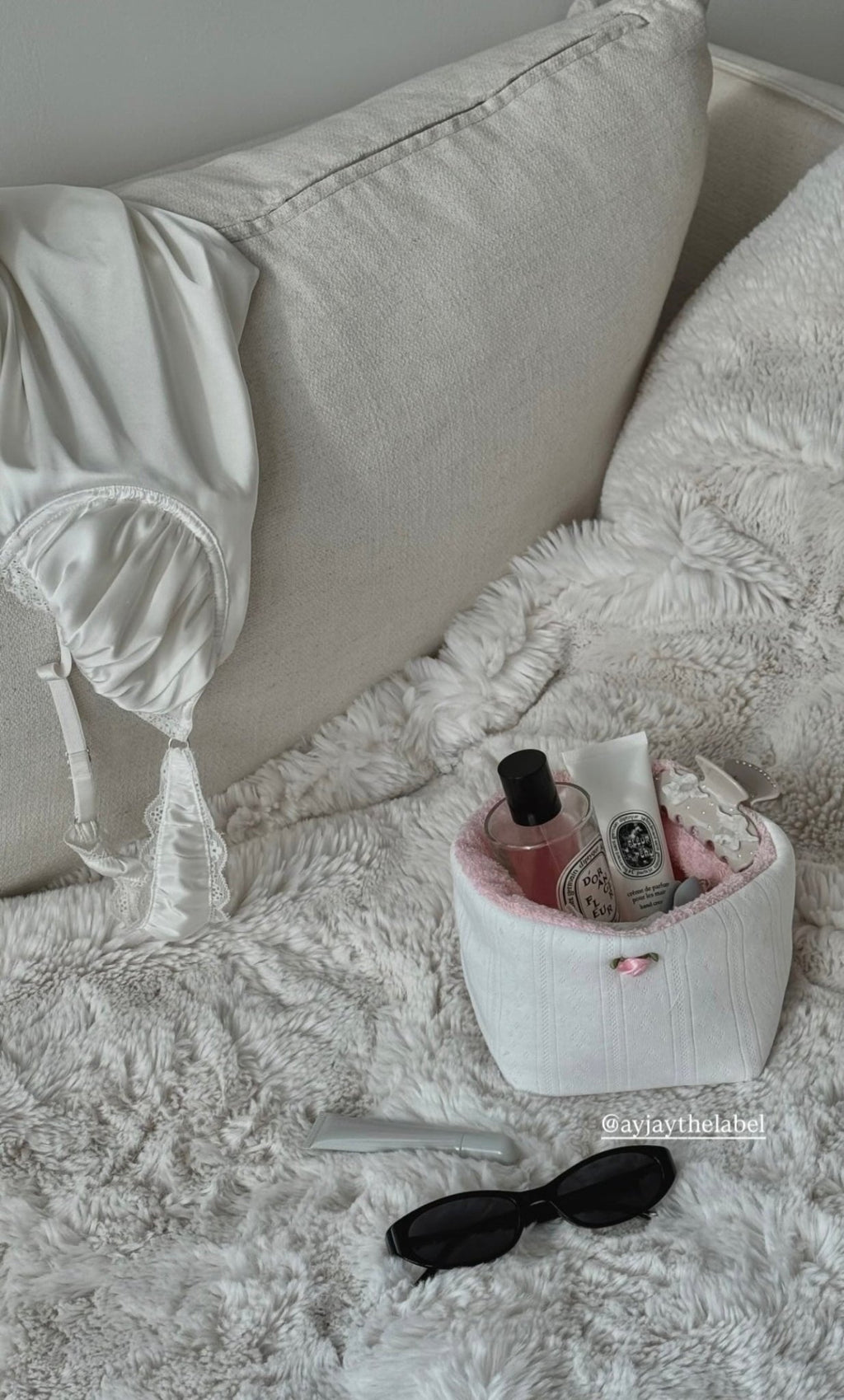 White jacquard lace knit organizer bin with pink bow, holding beauty bottles