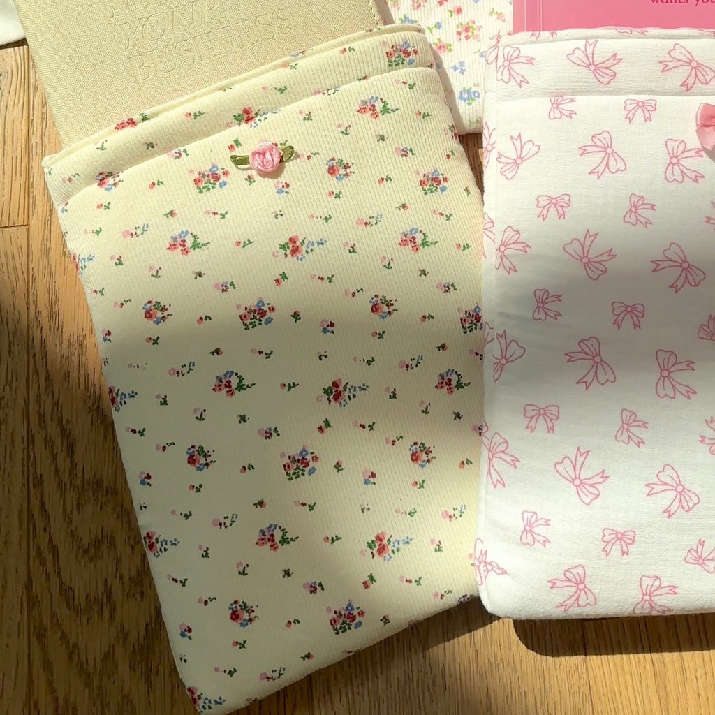 Cream Kindle book sleeve with mini floral sprig pattern and pink rose button center