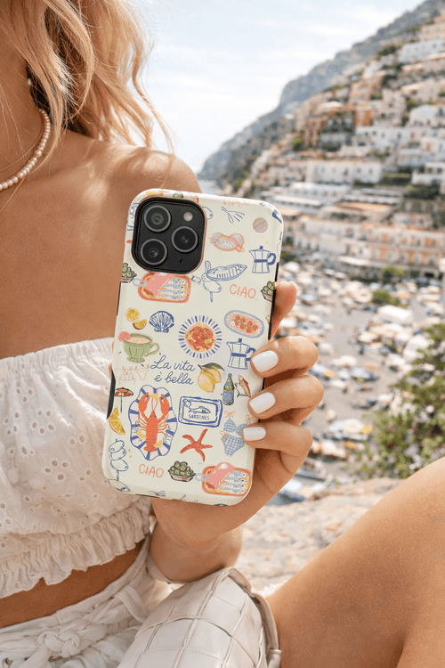 Phone case with “La vita è bella” seafood print, held in hand outdoors
