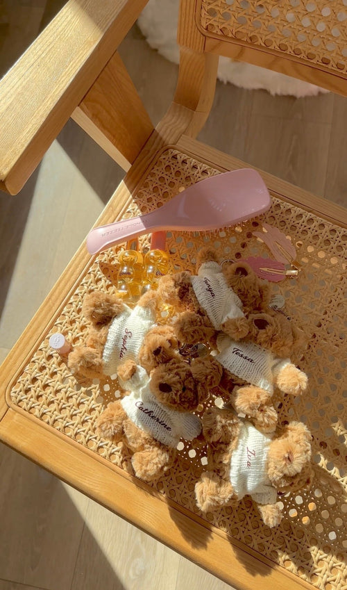 Teddy bear keychain bag charms in tray, brown bears with white sweaters and name patches
