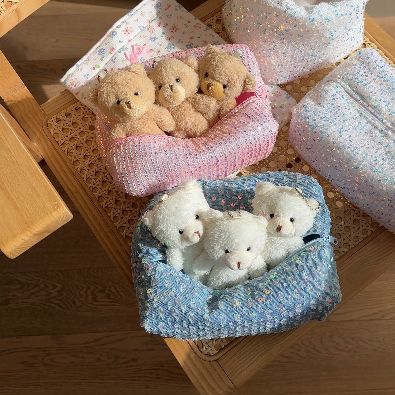 Pink and blue iridescent sequin zipper pouches, each holding teddy bears