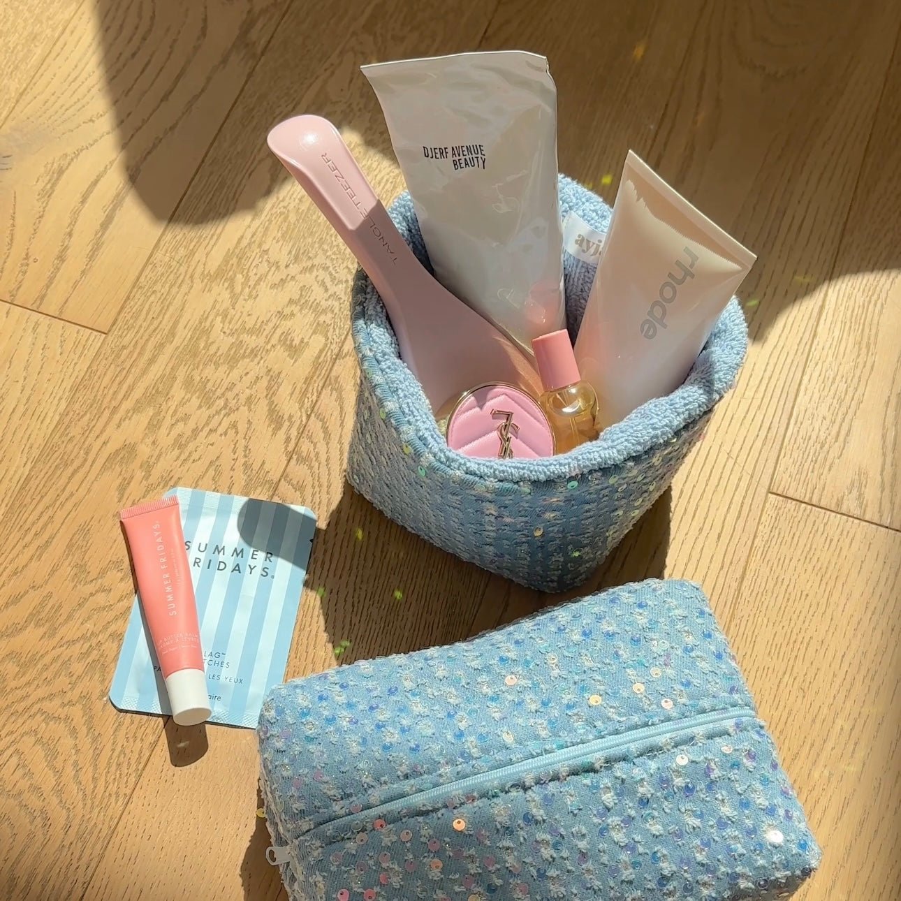 Light blue denim zip pouch with colorful floral speckle pattern, open top