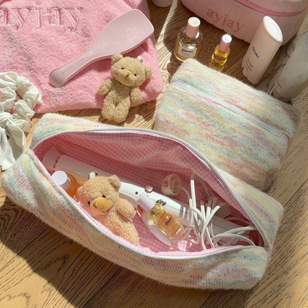 Pastel rainbow-striped toiletry pouch with pink gingham lining, open top.