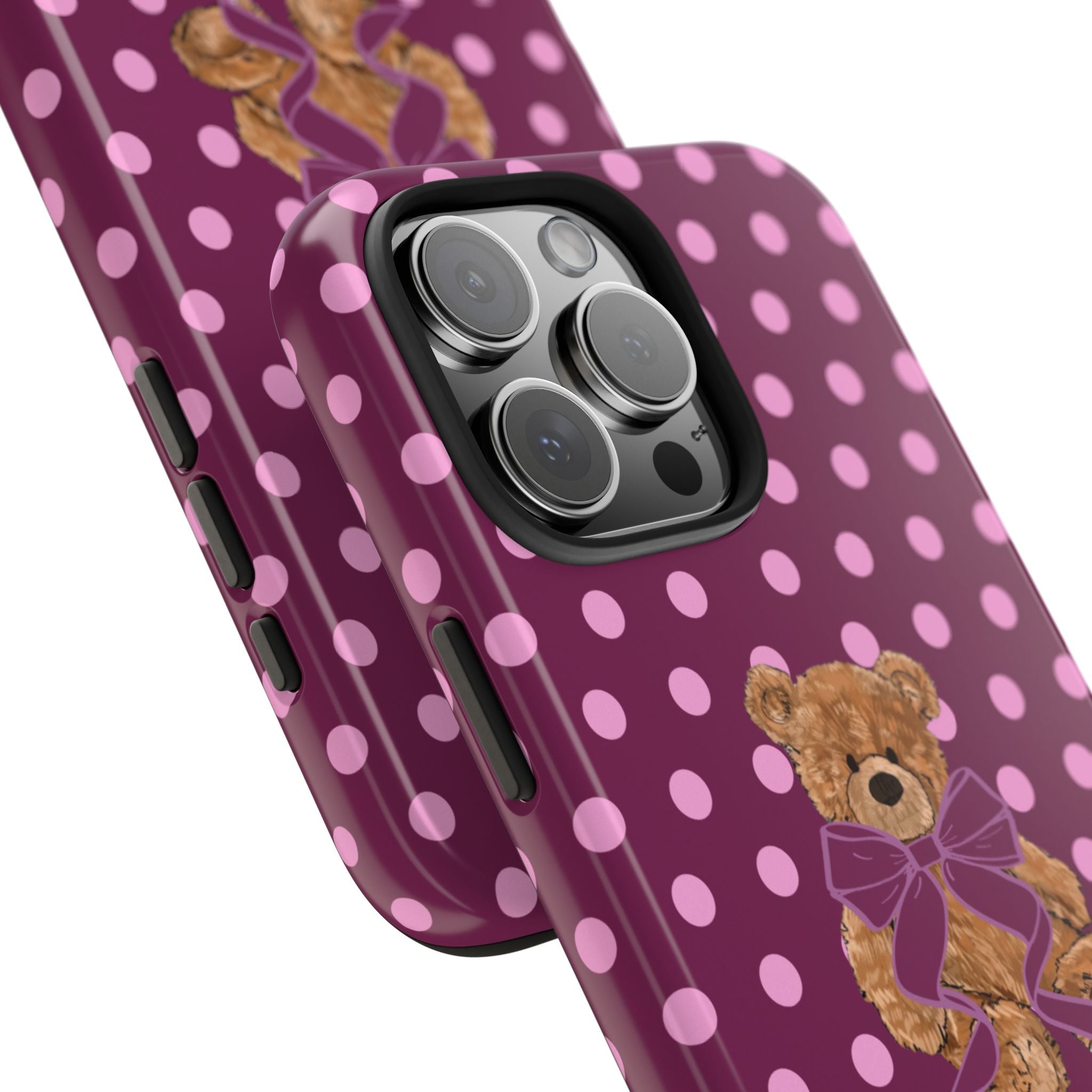 Angled magenta polka dot phone case with teddy bear and purple bow near camera cutout