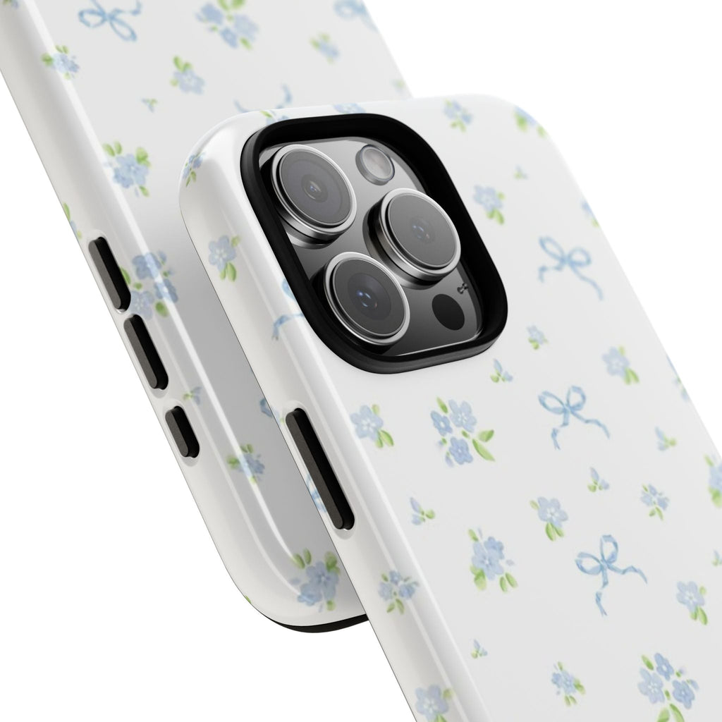 Angled view of white phone case with blue floral bow print; raised camera frame and buttons