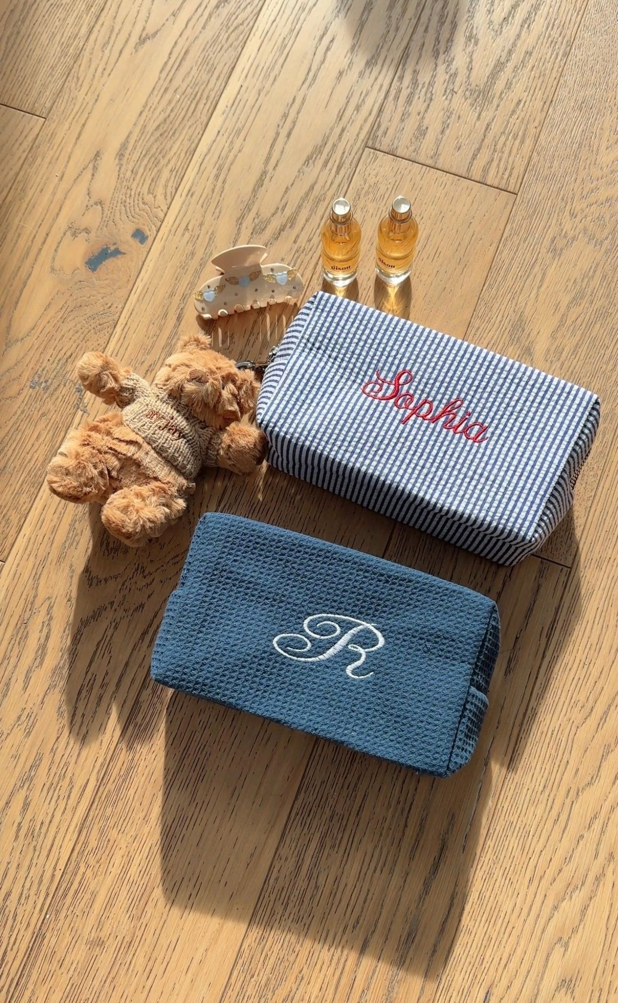 Navy blue striped zip pouch with red embroidered name, top view
