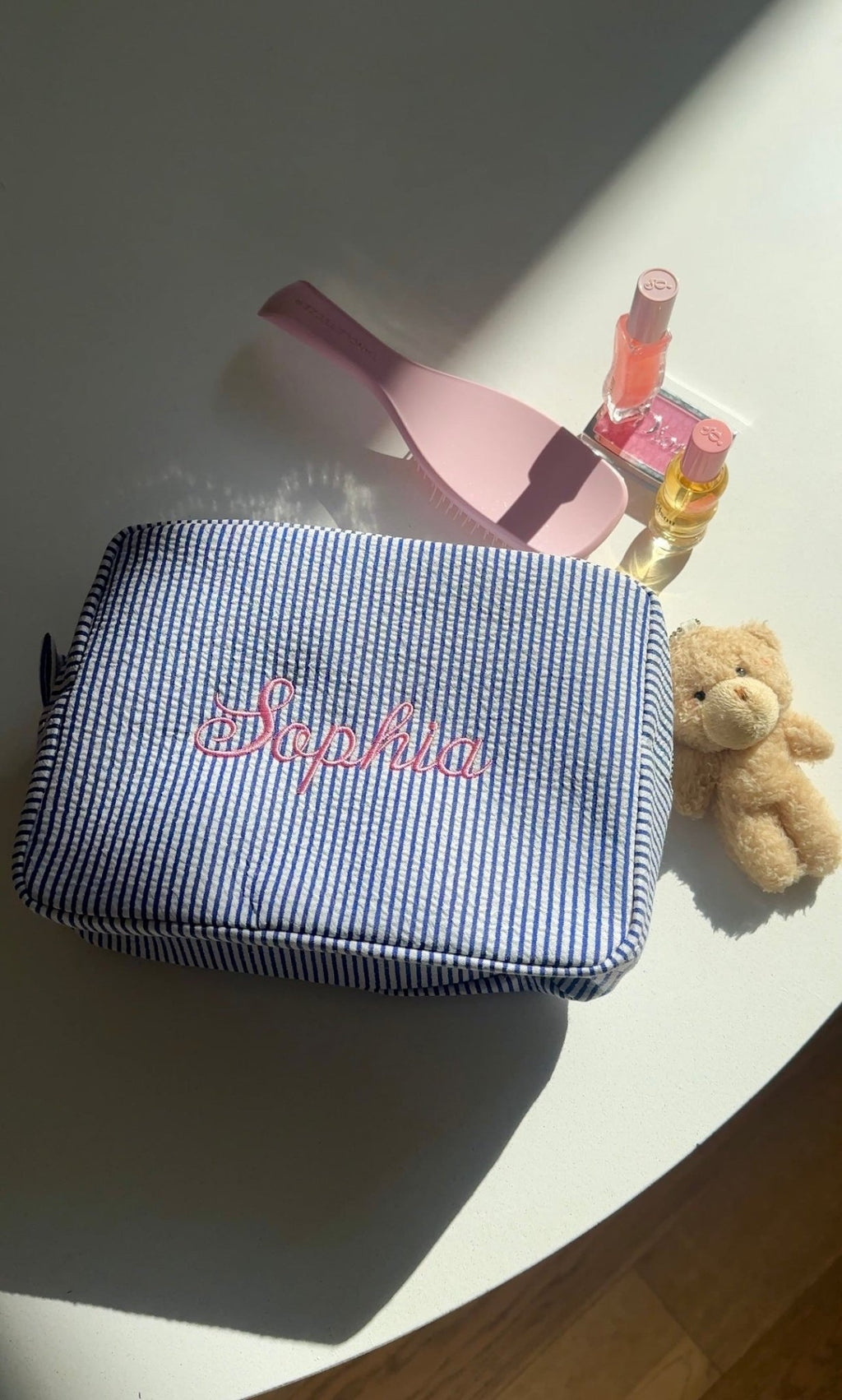 Navy blue striped zip pouch with pink embroidered name