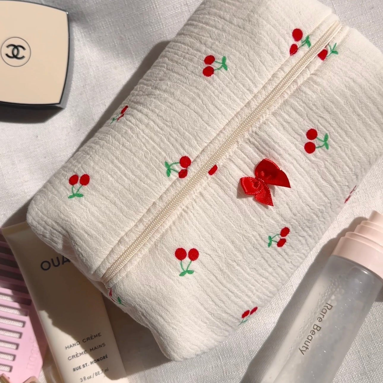 White textured zip pouch with cherry embroidery and small red bow detail