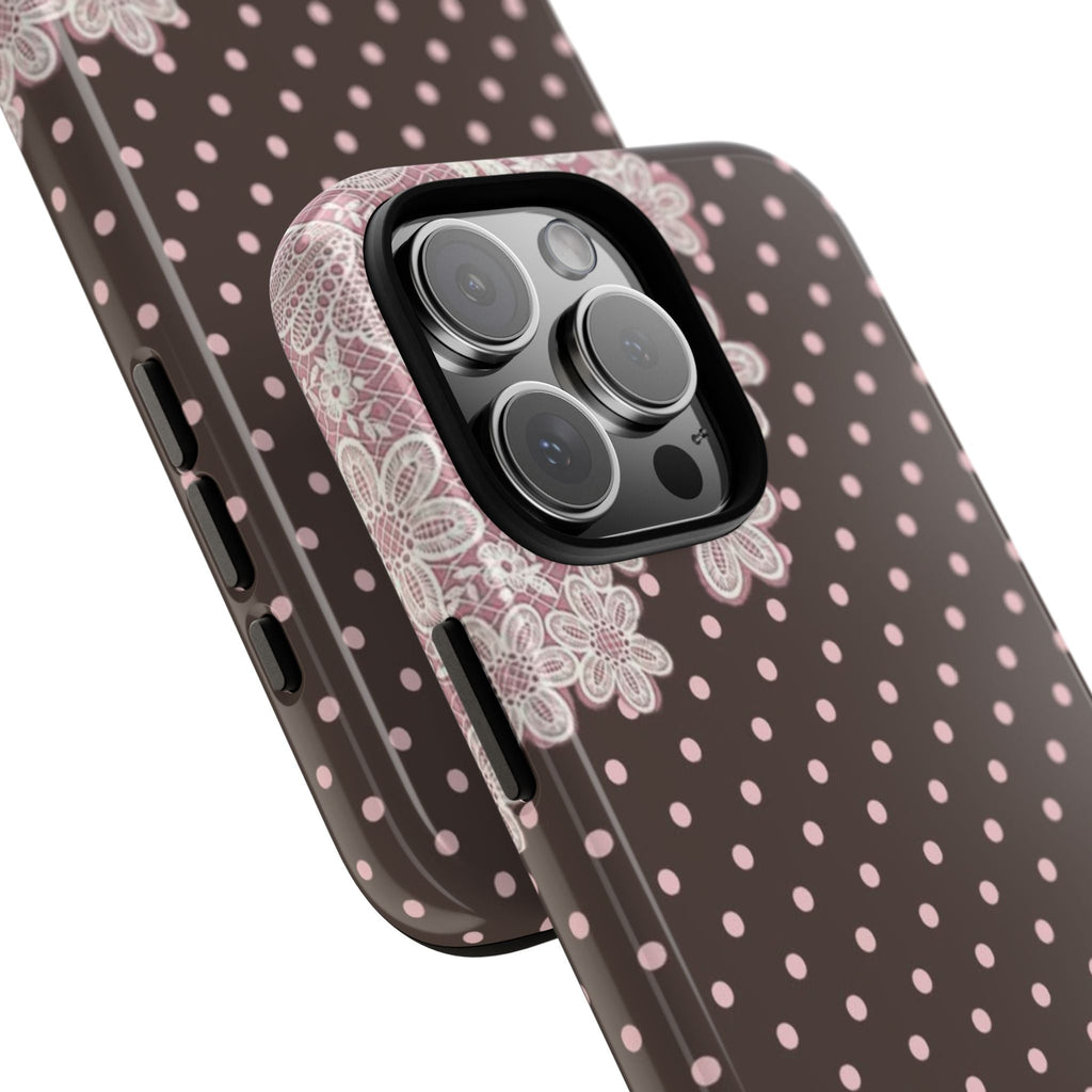 Close-up phone case corner: pink polka dot pattern with white lace near camera