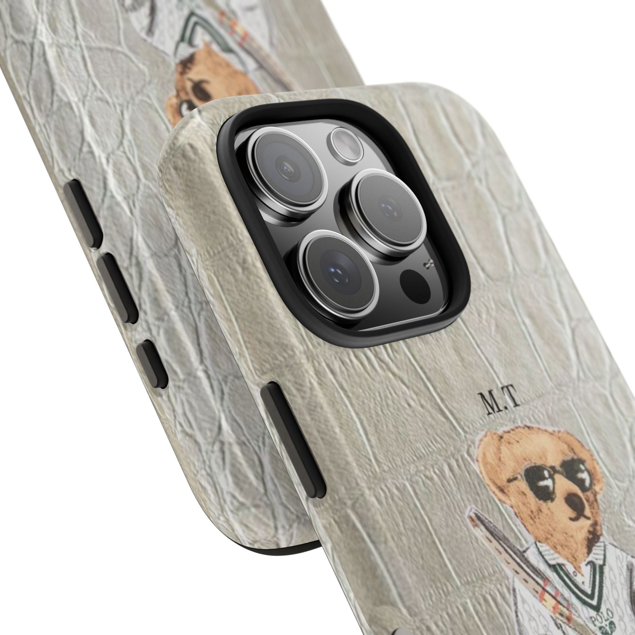 Close-up of beige crocodile-pattern phone case with camera cutout and teddy bear initials M.T.