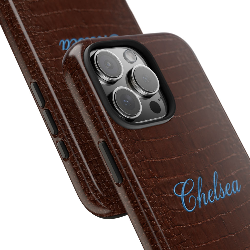 Angled view of brown croc phone case with blue 'Chelsea' name and side button cutouts
