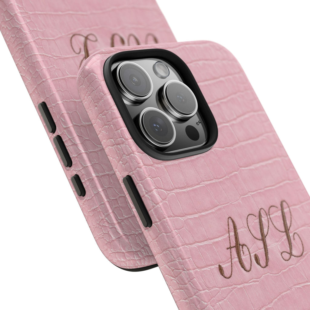 Overlapping pink croc phone cases with custom script initials and camera cutouts