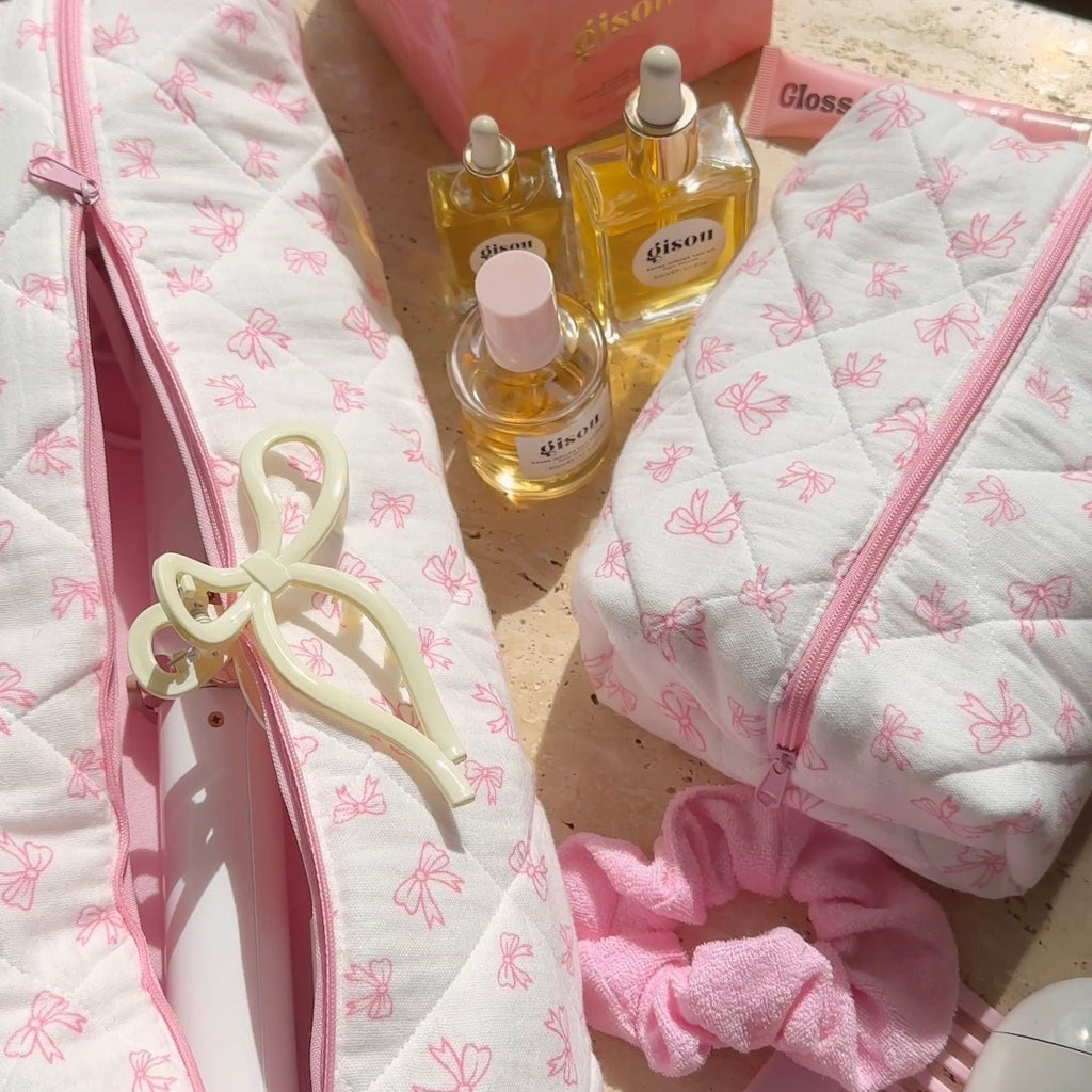 Two white bow-pattern pouches with pink zippers