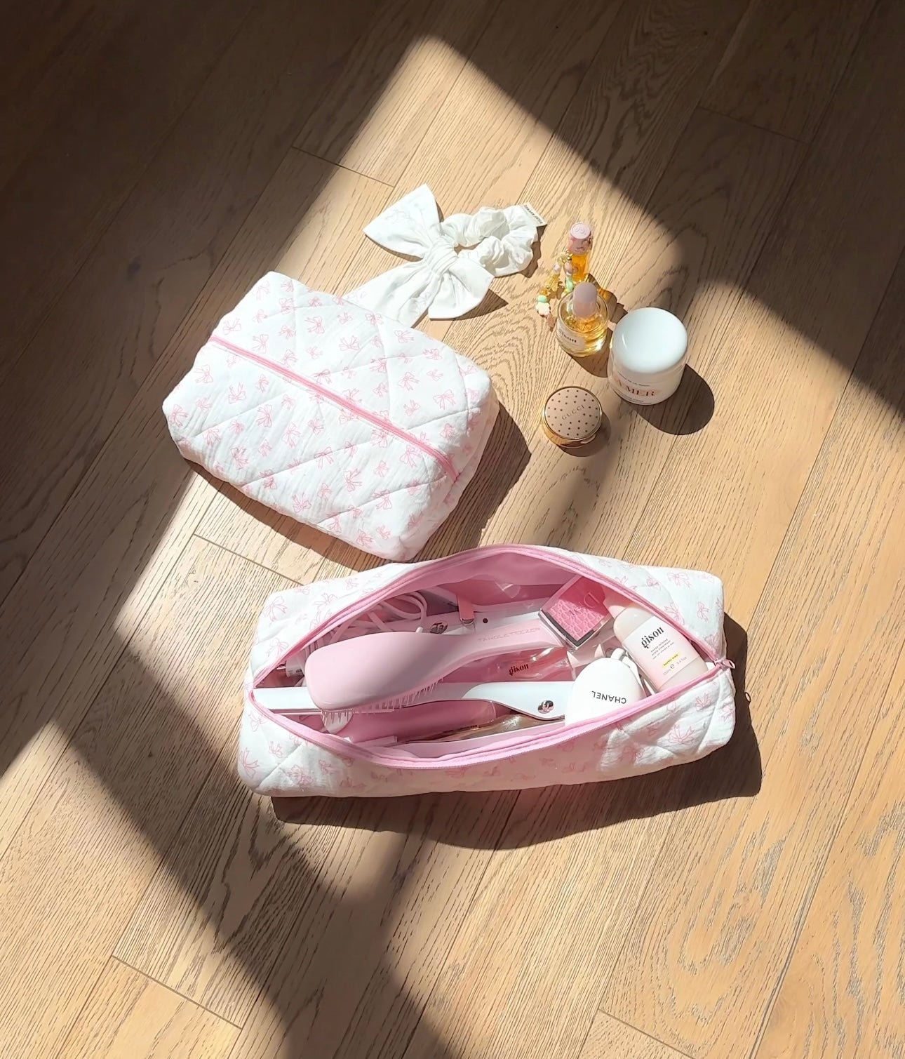 White quilted hair tool bag with pink bow pattern, open top with pink zipper and lining.