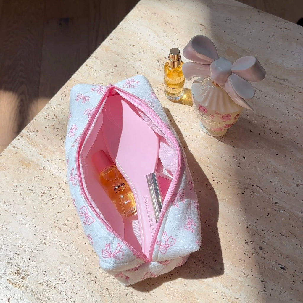 White bow-pattern pouch with pink zipper, open top view