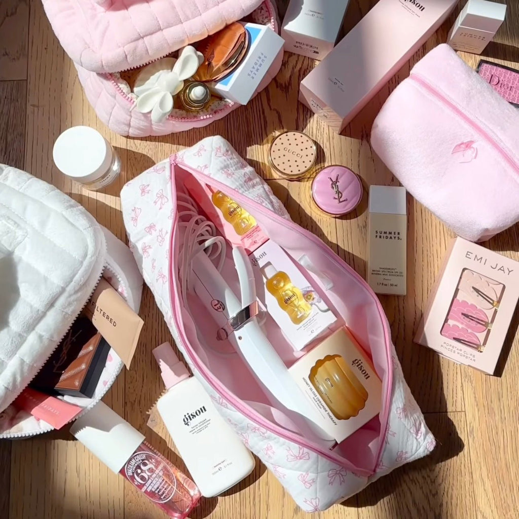 White quilted hair tool bag with pink bow pattern, open with pink-lined zipper front.