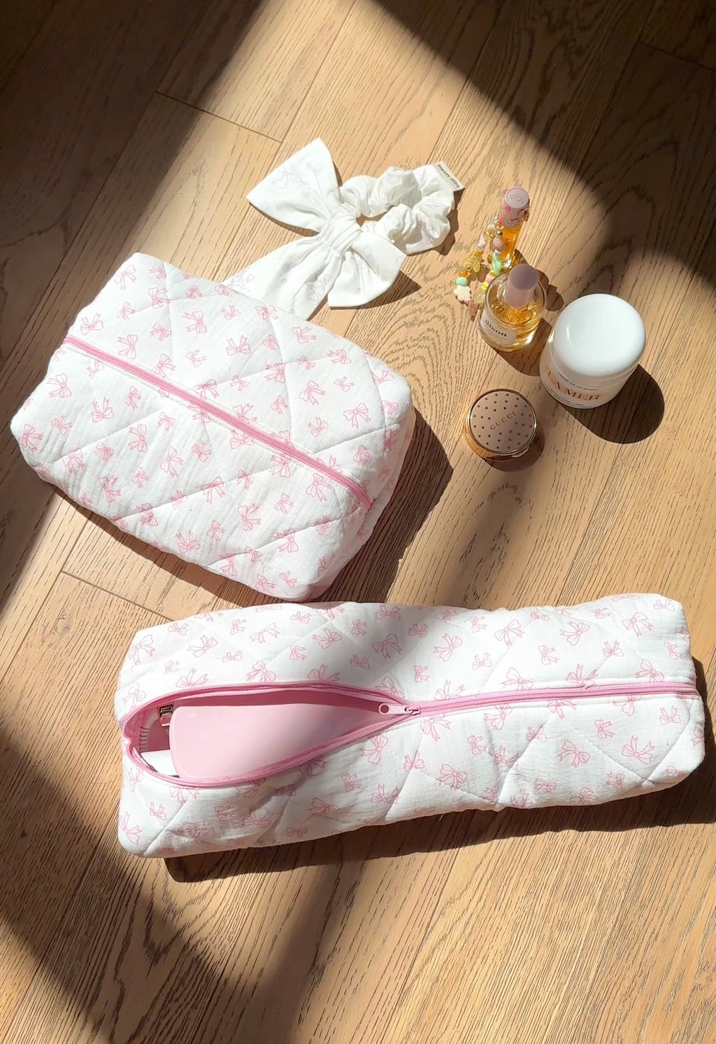 White quilted hair tool bag with pink bow pattern and pink zip trim, bow tied top.